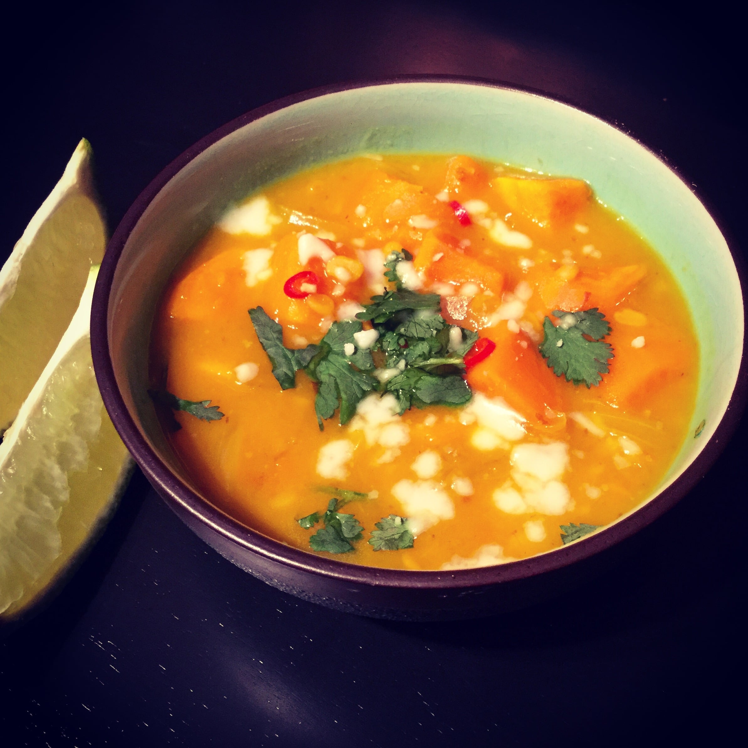 A bowl of Thai Sweet Potato and Lentil Curry with 2 wedges of fresh lime
