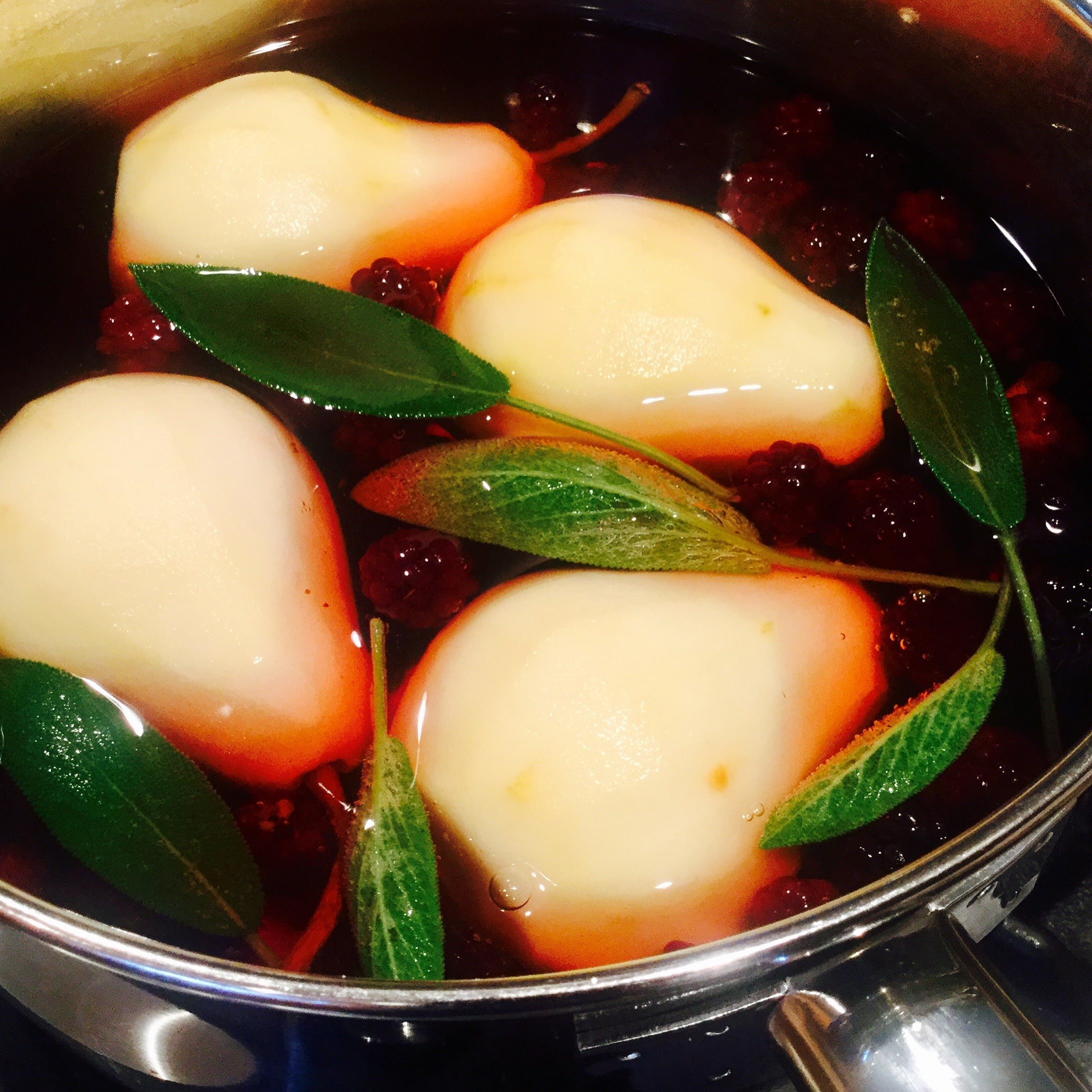 Poaching pears in blackberries apple juice and sage